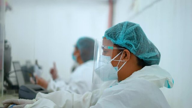 Female Nurse Wearing Personal Protective Equipment Typing on a Laptop Handheld Profile Shot 4k