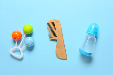 Wooden hair comb, rattle and bottle for baby on blue background