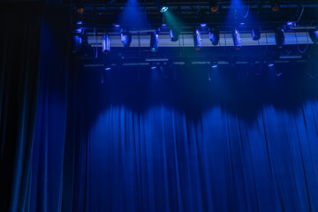 Many wide beamed spotlight shining straight down through smoky atmosphere in darkness with electrical element visible in light. Projector spotlight blue color on smoke texture background.