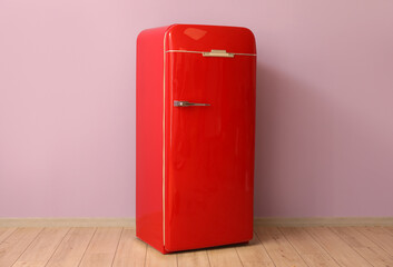 Stylish retro fridge near pink wall in room