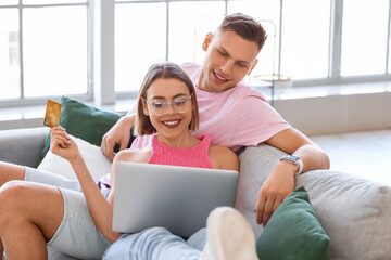 Fototapeta premium Young couple with laptop and credit card at home. Online shopping