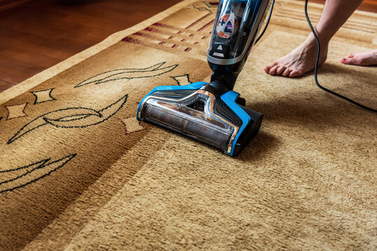Cordless vacuum cleaner is used to clean the carpet in the room.