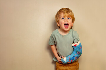 Laughing boy despite broken hand in plaster cast after accident - obrazy, fototapety, plakaty