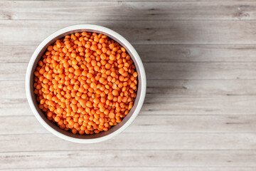 red lentils in bowl on wooden background 