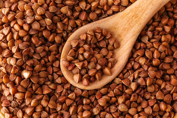 Wooden spoon on buckwheat grains, closeup