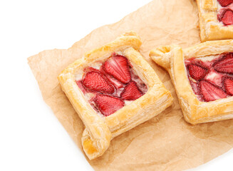 Parchment paper with strawberry puff pastries on white background