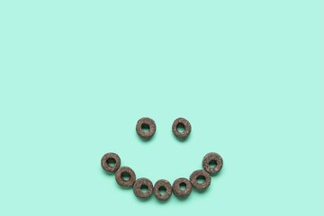 Smile made of black cereal rings on blue background