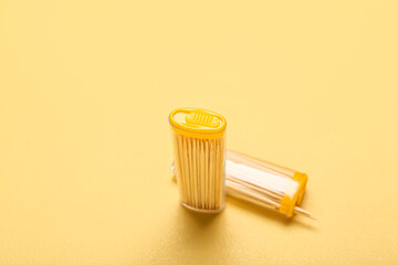 Holders with wooden toothpicks on yellow background