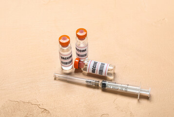 Ampules of monkeypox vaccine and syringe on beige background