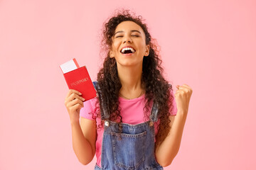 Young African-American woman with passport and ticket on pink background - obrazy, fototapety, plakaty