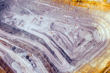 Top view of an iron ore quarry. Excavator loading ore into train cars. Environmental pollution problems.