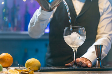 Barman making cocktail in night club adding ingredients and creating expert drinks on bar counter copy space.