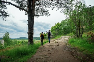 Father and son tourists walk along a mountain forest road in a natural park in northern Europe