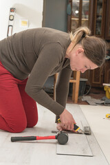 Woman master cuts quartz vinyl floor with a stationery knife, floor installation.