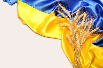 Wheat spikelets and flag of Ukraine on light background