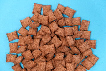 Sweet breakfast cereal dry - chocolate pads made of cereals on a blue background, viewed from above.