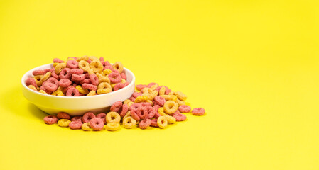 Quick cereal breakfast in the form of rings on a plate on a yellow background