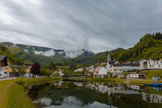 Panorama of the city of Reichraming a small town in central austria on a cloudy day. Visible reflection of the village over the river running through it.