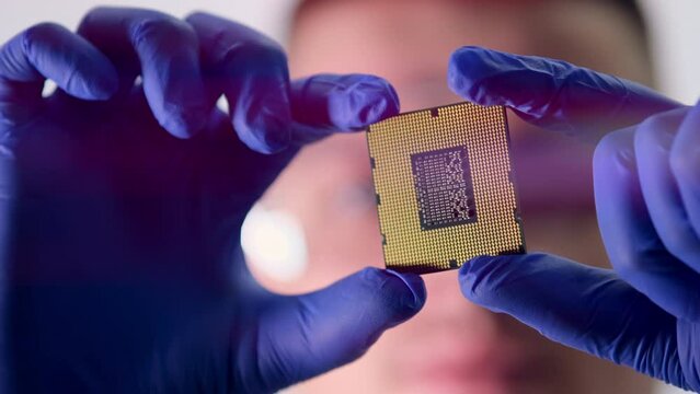 The concept of computer technology: An engineer in a sterile jumpsuit holds a computer microchip in his gloves and examines it. The concept of artificial intelligence