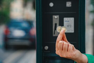 Woman holding euro coins in front of car parking machine.