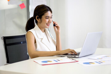 Young asian businesswoman adjusting the headset with mic prepare for online meeting through laptop computer. Working concept social distancing, quarantine, and isolation