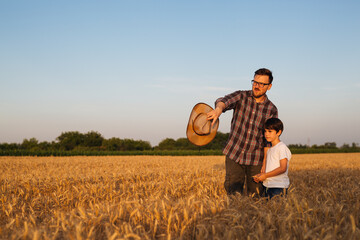 father showing to his son their land. standing in wheat field