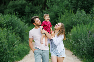 Fototapeta premium A happy and joyful family with a young son walks through the forest in the summer. Healthy lifestyle