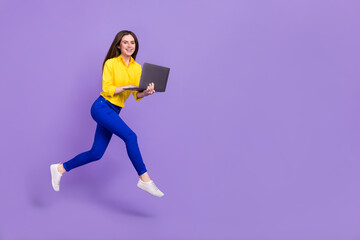 Full length body size view of attractive trendy girl jumping using laptop copy space isolated over bright violet purple color background