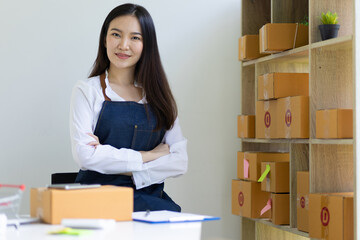 Portrait of a woman, a small start-up business owner working in a home office with parcel boxes for shipping online orders from the Internet.