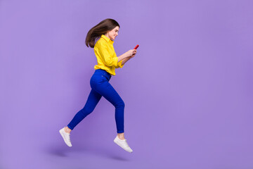 Fototapeta na wymiar Full length body size view of beautiful trendy cheery girl jumping using device isolated over bright violet purple color background
