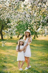 Beautiful and happy mother and daughter in a blooming spring garden. Parental love on Mother's Day.