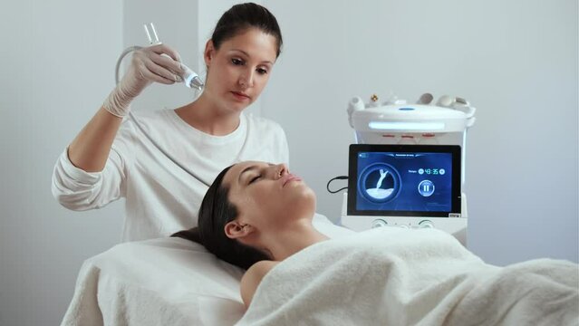 Video of cosmetologist making ultrasonic cleaning and rejuvenation the face to beautiful woman on the spa center.
