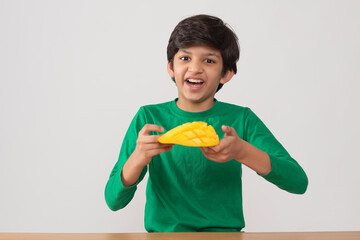 Portrait of happy boy holding a segmented slice of mango