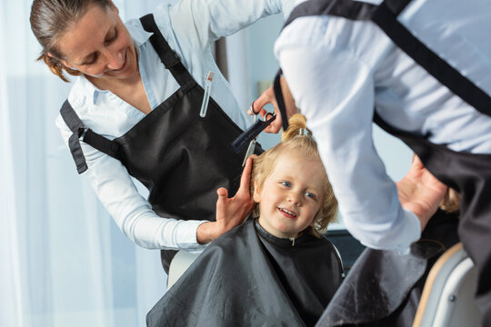 Portrait through mirror of hairdresser make haircut to a boy