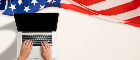 Workplace with modern laptop, letters and USA flag near light wall