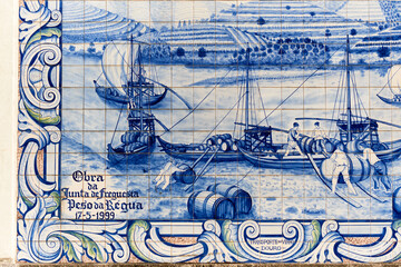 panels of azulejos, tiles, showing the transport of barrels by boat on the railway station of Peso da Regua, Portugal