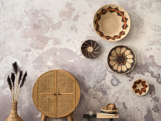 The stylish ethnic composition at living room interior with copy space, colorful baskets, rattan sideboard and elegant personal accessories. Grey concrete wall. Cozy apartment. Home decor.