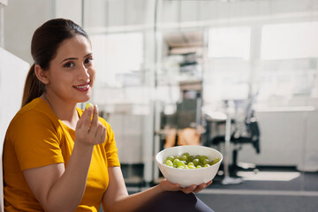 Portrait of a happy young woman eating grapes