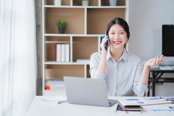 Young asian businesswoman beautiful charming smiling and talking on the mobile phone in the office