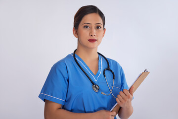 Portrait of a female nurse standing with clipboard in hand against white background
