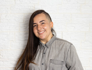 Trendy girl with unusual hairstyle posing for photo. Neutral, gray colors.