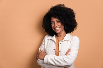 happy black young woman with arms crossedwearing white jacket in studio shot. portrait, real people...