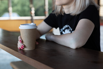 a girl sits at a table with a glass of coffee without inscriptions