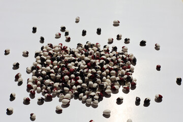 Macro view of black and white haricot bean. Pile of two colors legumes close up on a white paper background.