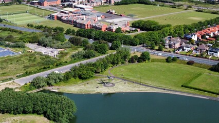 Fototapeta na wymiar Aerial view of Fairhaven lake in Lytham St Annes with views of fields and buildings in the background. 