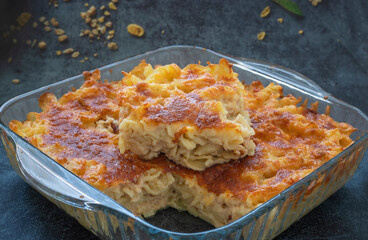 Pasta casserole bechamel sauce topped with melted mozzarella cheese and served in a white baking dish on a table (Turkish name; firinda makarna or firin makarna)