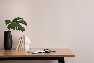 The stylish composition of cozy office interior with copy space, vase with leaf, wooden table and...
