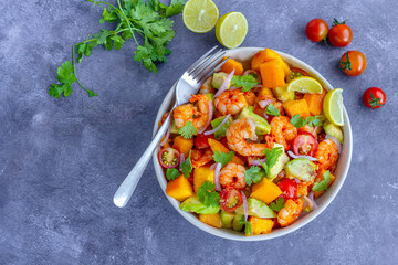 Fototapeta na wymiar Healthy Shrimp Mango Salad with Avocado, Cherry Tomatoes and Onion, Garnished with Fresh Cilantro