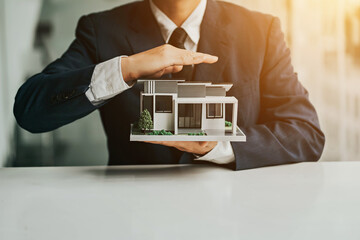 hand of young man customer signing contract for buying house with real estate broker in suit at estate agent office, investment, home loan contract, buying house, real estate and insurance concept