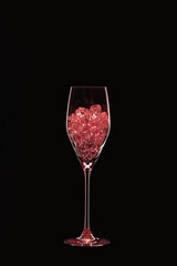 Naklejka na ściany i meble Champagne flute filled with transparent pink crystals backlit and isolated on black background. Beverage glassware concept. Copy space.